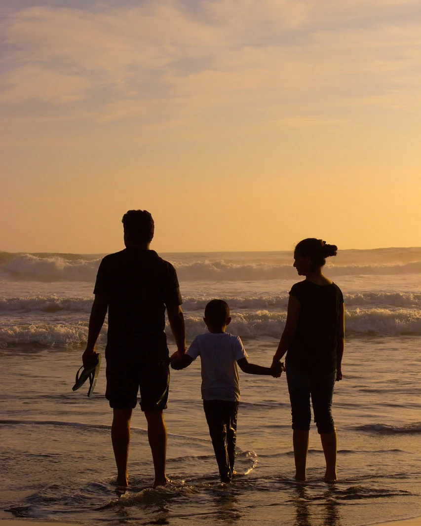 Familie am Meer bei Sonnenuntergang, Hand in Hand